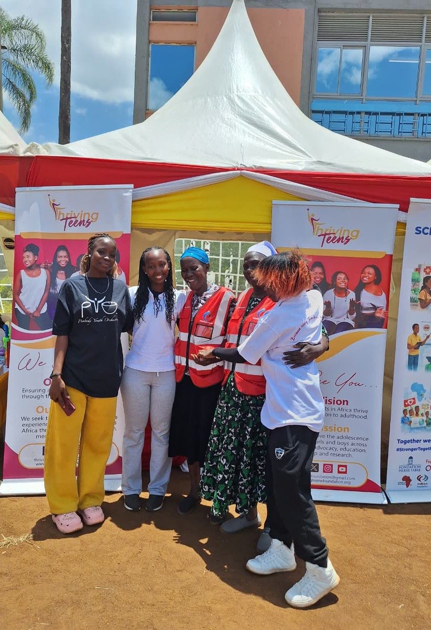 Thriving Teens Foundation team hugging at a community outreach tent