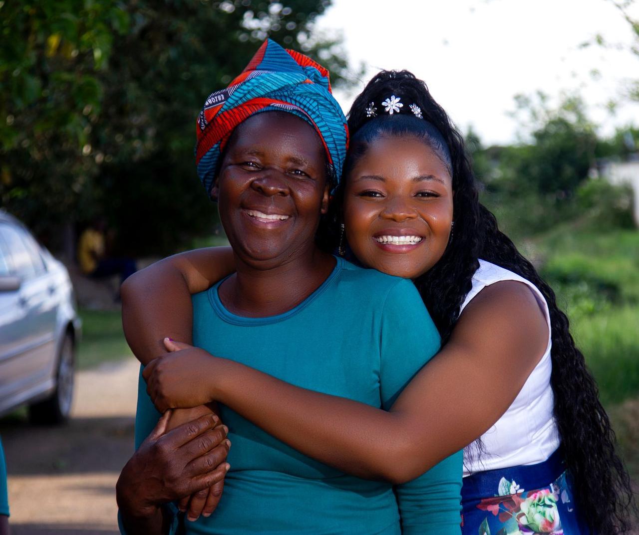 A mother and her teenage daughter hugging and smiling