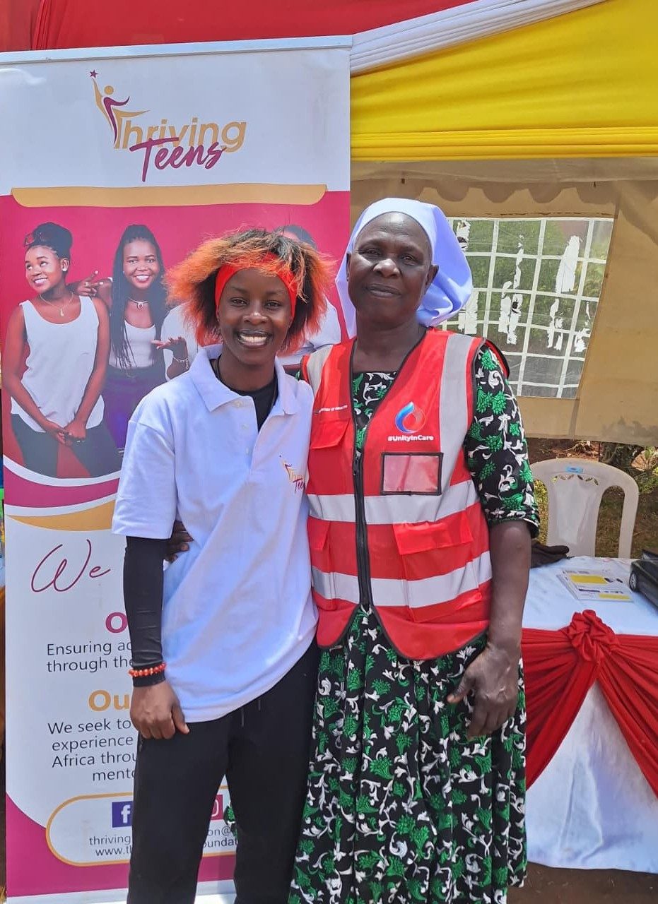 Thriving Teens volunteer with a community health partner at an outreach tent